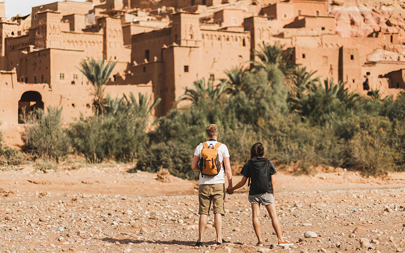 Couple of backpacker travelers on background Ait Ben Haddou ksar in Ouarzazate. Welcome to Morocco.
